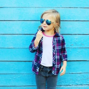 A little girl wearing sunglasses and plaid shirt.