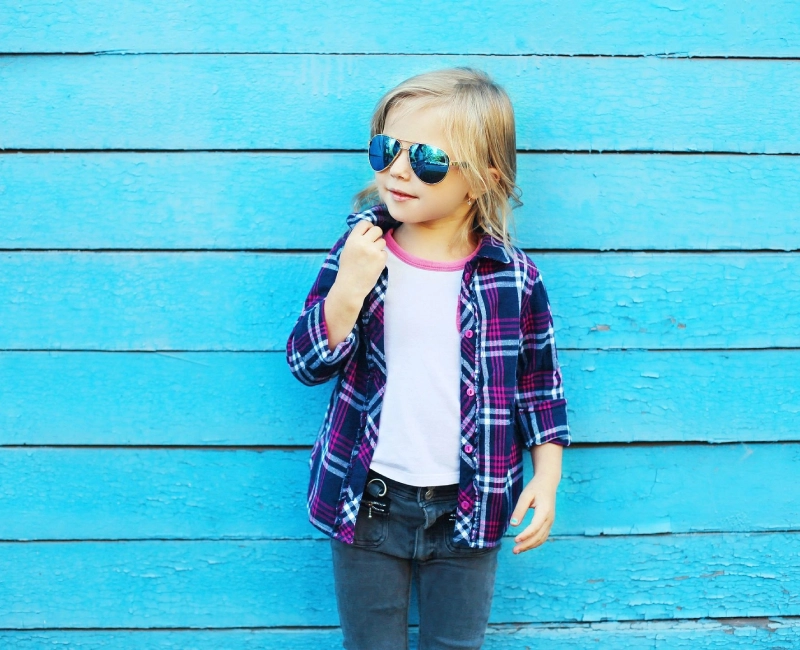 A little girl wearing sunglasses and plaid shirt.