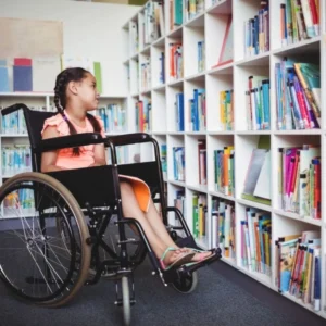 A girl in a wheelchair is sitting on the floor