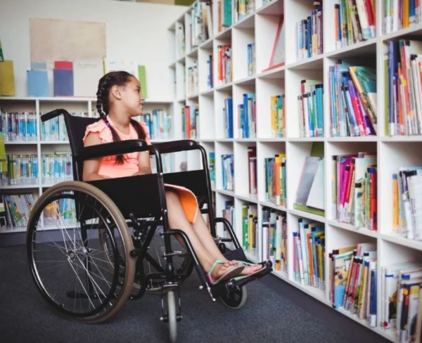 A girl in a wheelchair is sitting on the floor