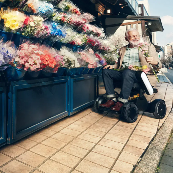 A man sitting in an electric scooter next to flowers.