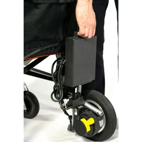 A person is holding the handle of an electric wheelchair.