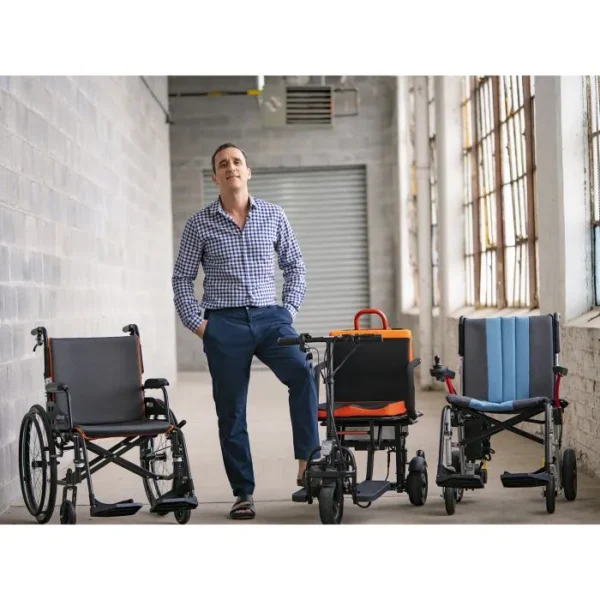 A man standing next to three different wheelchairs.