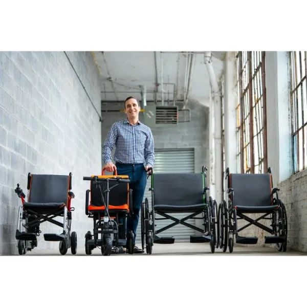 A man standing next to several wheelchairs.