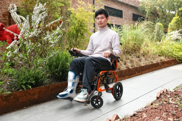 A man in white shirt and black pants riding on a orange scooter.