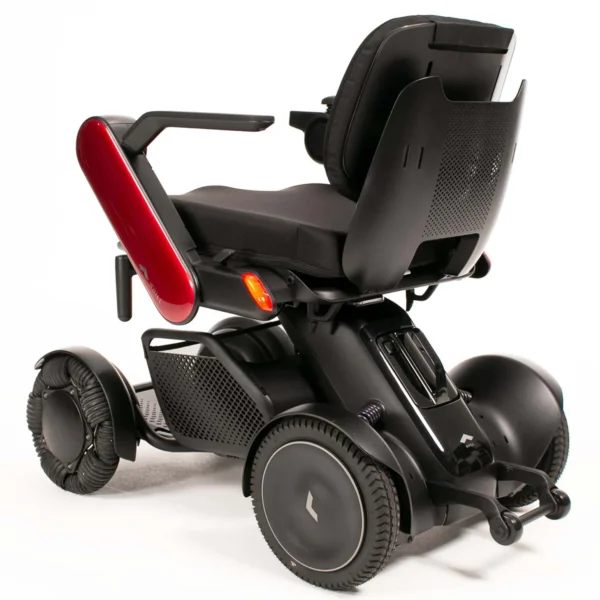 A black wheelchair with red seat and wheels.