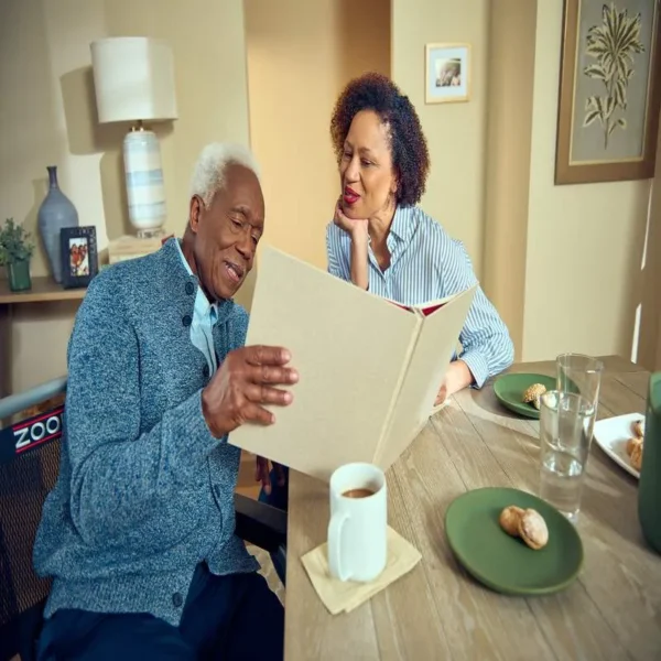 A man and woman sitting at the table looking at an album.