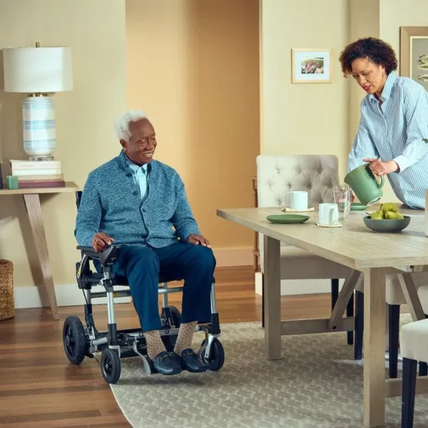 A man in a wheelchair and woman in a dining room.